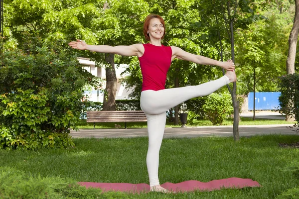 Lächelndes Mädchen im Park Übung auf der Yogamatte, hoher Ausfallschritt — Stockfoto