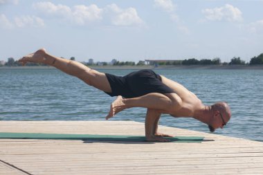 Doğada ahşap zeminde yoga yapan adam