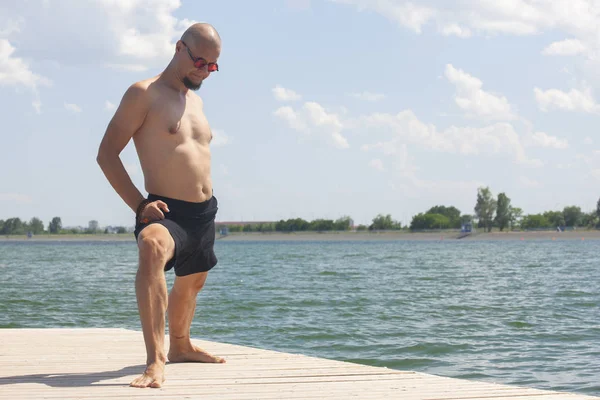 Young man doing yoga and meditating in warrior pose on beach — Stock Photo, Image