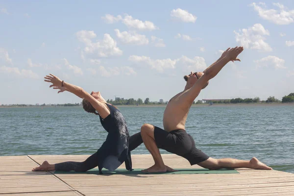 Mutlu çift sahilde su yanında yoga yaparken