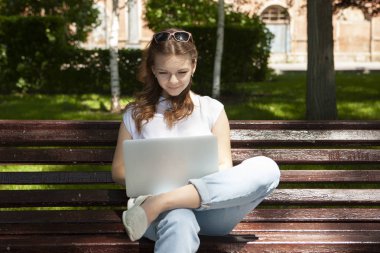 bir dizüstü bilgisayar ile bir tezgah üzerinde oturan güzel genç öğrenci kız