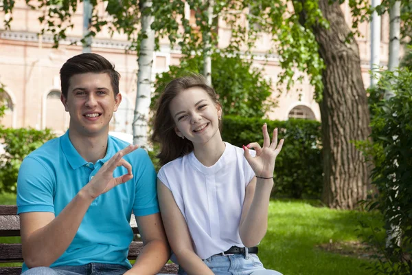 Vackert ungt par sitter på en bänk i parken — Stockfoto