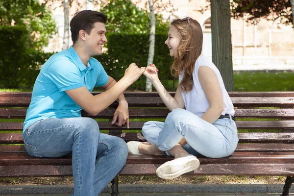 Hermosa pareja joven sentada en un banco en el parque — Foto de Stock