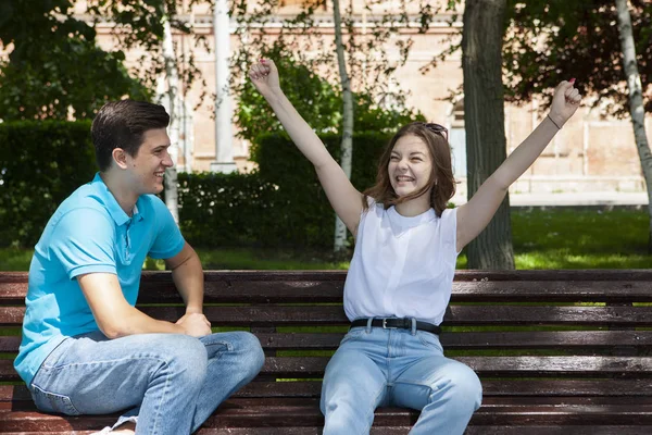 Hermosa pareja joven sentada en un banco en el parque — Foto de Stock