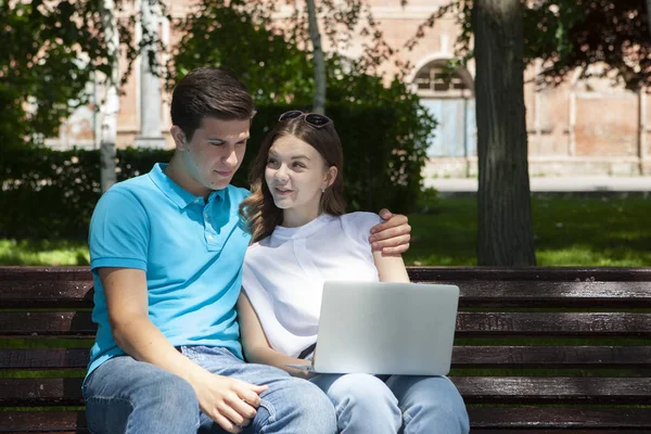 Joven pareja guapa usando cuaderno en el parque público — Foto de Stock