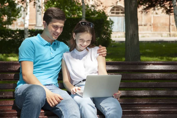 Joven pareja guapa usando cuaderno en el parque público — Foto de Stock