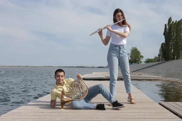 호수에서 플루트를 연주하는 뿔과 소녀를 연주하는 사람 — 스톡 사진