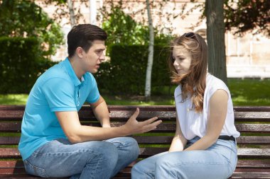 Parktaki ahşap bankta otururken birbirleriyle konuşmayan çelişkili çiftler.