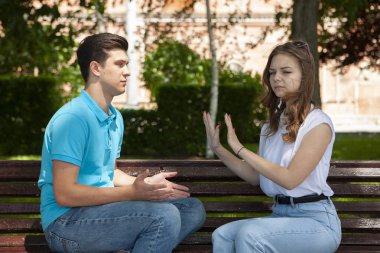 Parktaki ahşap bankta otururken birbirleriyle konuşmayan çelişkili çiftler.