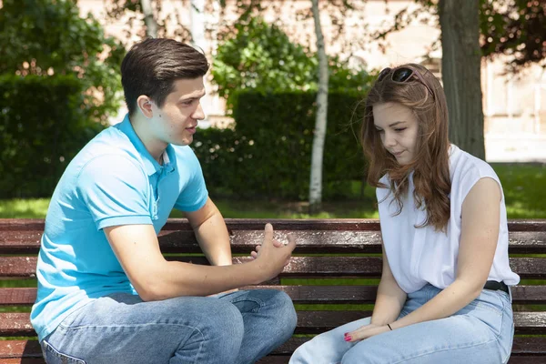 Conflicted couple not talking to each other seated on a wooden bench in park