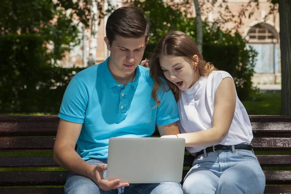 幸福的年轻夫妇使用笔记本电脑坐在长椅上的 cit — 图库照片