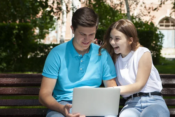 Feliz jovem casal usando laptop computador sentado no banco em cit — Fotografia de Stock