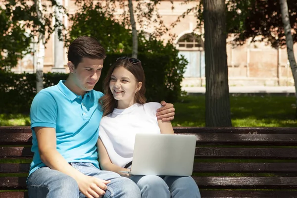 Joven pareja guapa usando cuaderno en el parque público — Foto de Stock