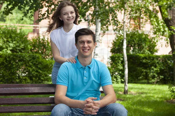 Beau jeune couple assis sur un banc dans le parc — Photo