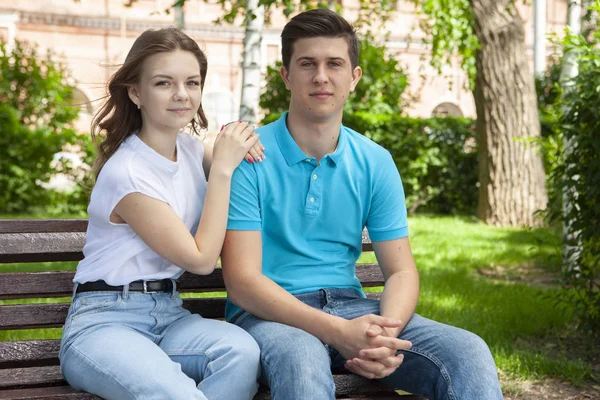 Hermosa pareja joven sentada en un banco en el parque — Foto de Stock