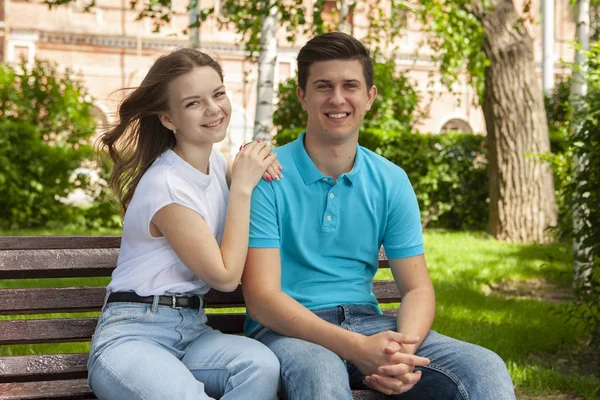Mooi jong paar zitten op een bank in het park — Stockfoto