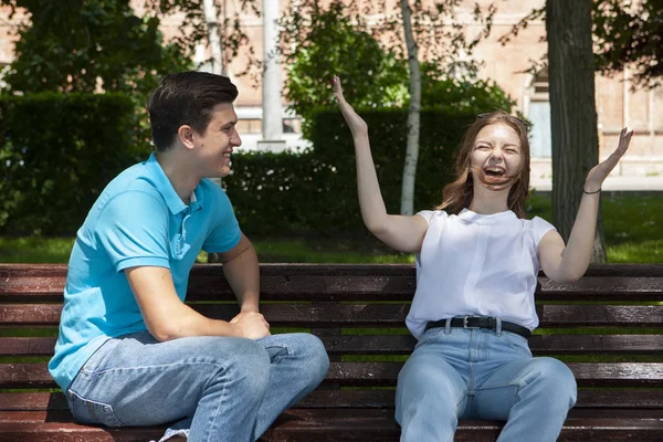 Hermosa pareja joven sentada en un banco en el parque — Foto de Stock