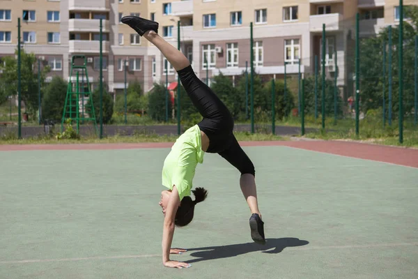 Fit running young girl athlete flies through the air while running makes a twine in the air doing a run in a city summer park. Concept of good stretching and excellent physical shape. — Stock Photo, Image