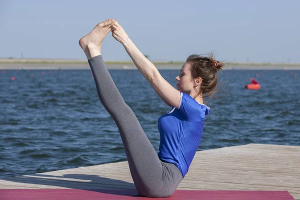 Junges Mädchen praktiziert Yoga am Ufer des Sees, das Konzept, Privatsphäre und Konzentration zu genießen, Sonnenlicht — Stockfoto