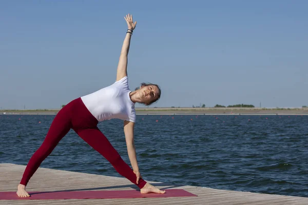Bella donna che pratica yoga in un lago — Foto Stock
