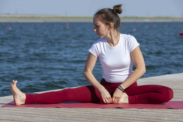 Ung kvinna som gör yoga i morgonparken nära sjön — Stockfoto