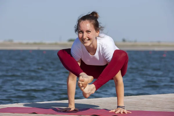 Ragazza che pratica yoga vicino al lago, godendo bella giornata nella natura e l'energia positiva . — Foto Stock