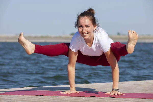 Ragazza che pratica yoga vicino al lago, godendo bella giornata nella natura e l'energia positiva . — Foto Stock