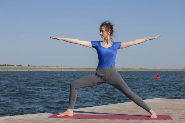 Giovane ragazza pratica yoga sulla riva del lago, il concetto di godere di privacy e concentrazione, luce del sole — Foto Stock