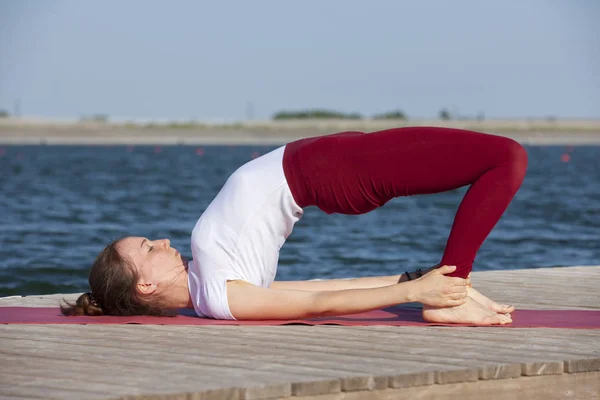 Wanita muda yang cantik berlatih yoga di luar ruangan di pagi hari — Stok Foto