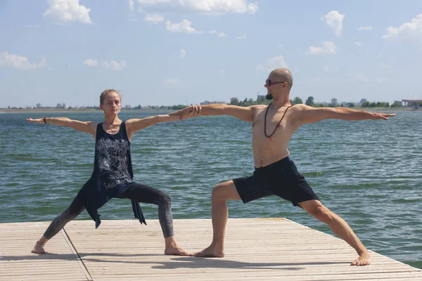 Yoga inspiration. Top view - couple of cheerful healthy beautiful slim man and woman are doing virabhadrasana