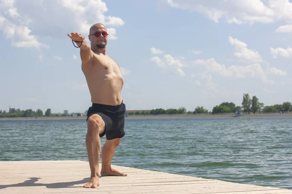 Young man doing yoga and meditating in warrior pose on beach — Stock Photo, Image