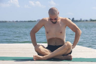 Genç adam lotus pozisyonunda yoga egzersizi yapıyor.