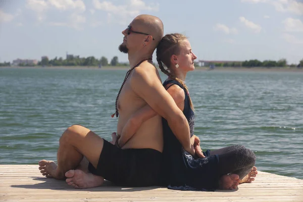 人と妊娠中の女性は、ビーチでヨガをやっています。 — ストック写真