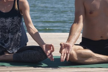 Çekici erkek ve kadın lotus yoga eller kadar yakın poz. Genç bir çift işten sonra bedenlerini ve ruhlarını meditasyon için yoga yapıyor. Dışarıda yoga yapan iki kişi..