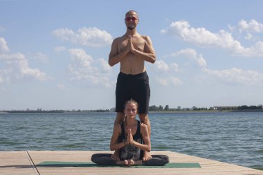 Güzel çift göl yakınında açık havada sabah akrostiş yoga. Denge ve bağlantı kavramı.