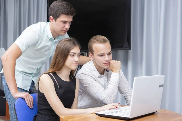 Gruppe von zwei jungen, euphorischen Studenten, die sich Prüfungsergebnisse in einem Laptop in einer Tabelle ansehen — Stockfoto