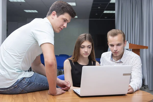 Gruppe von zwei jungen, euphorischen Studenten, die sich Prüfungsergebnisse in einem Laptop in einer Tabelle ansehen — Stockfoto