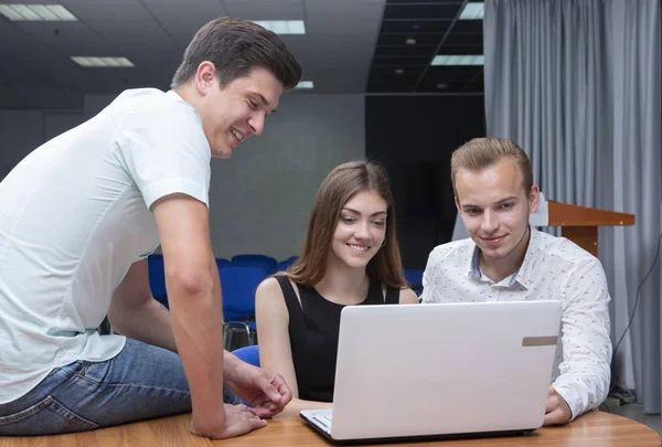 Gruppe von zwei jungen, euphorischen Studenten, die sich Prüfungsergebnisse in einem Laptop in einer Tabelle ansehen — Stockfoto
