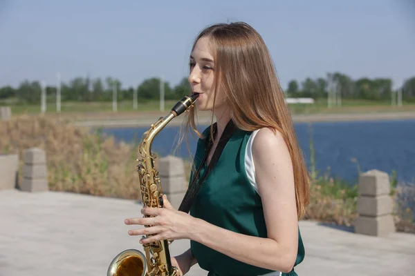 Young woman with saxophone in the park — Stock Photo, Image