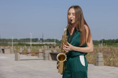 Güzel esmer parkta saksafon çalış