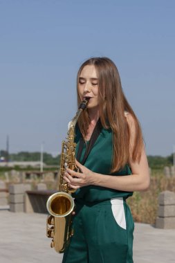 Güzel esmer parkta saksafon çalış