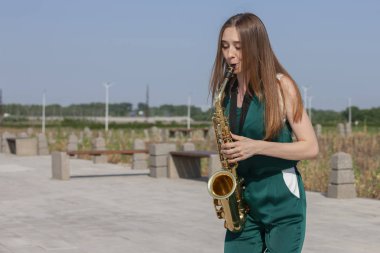 Güzel esmer parkta saksafon çalış