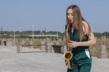 Güzel esmer parkta saksafon çalış