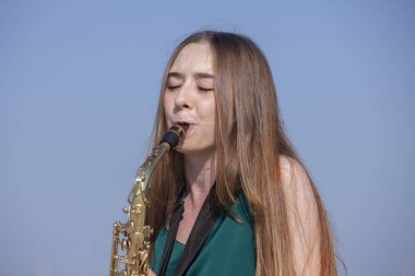 Güzel esmer parkta saksafon çalış