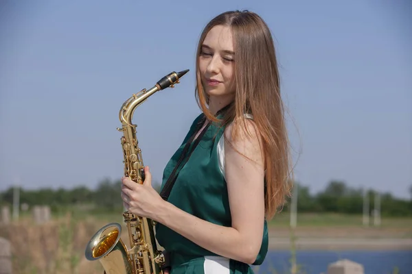 Young woman with saxophone with nature background — Stock Photo, Image