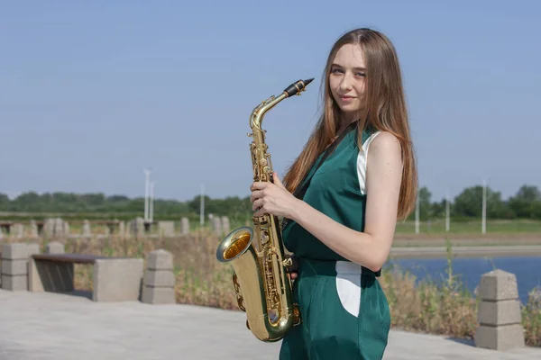 Mujer joven con saxofón con fondo natural — Foto de Stock