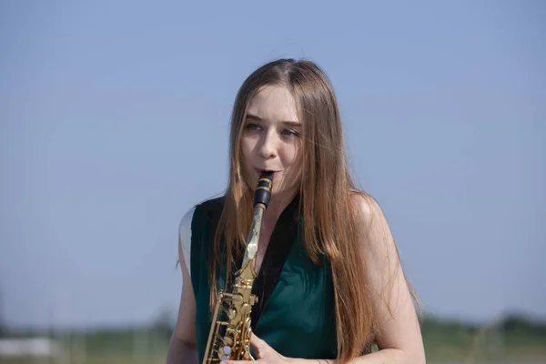 Linda morena toca saxofone no parque — Fotografia de Stock