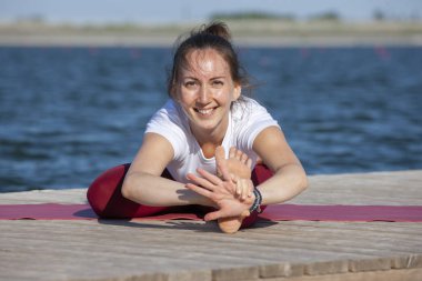 Genç kız uygulamaları yoga göle zevk gizlilik ve konsantrasyon, güneş ışığı kavramı kıyısında