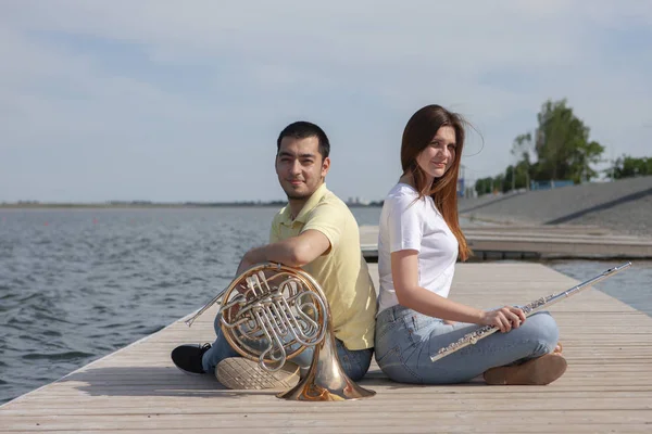 Der Mann, der das Horn spielt und das Mädchen, das die Flöte auf dem See spielt — Stockfoto