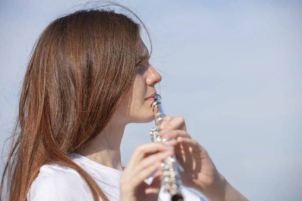 Dívka hrající na flétnu v zahradě. — Stock fotografie